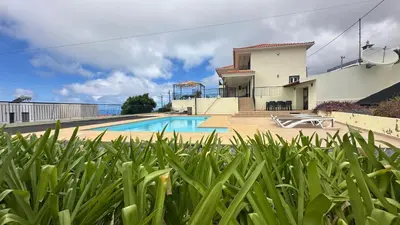 a villa with a swimming pool in front of a house at Casa Estrelada in Estreito da Calheta