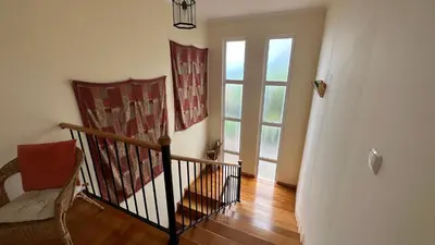a room with a staircase with a window and a chair at Casa Estrelada in Estreito da Calheta