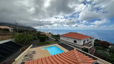 a house with a swimming pool next to the ocean at Casa Estrelada in Estreito da Calheta