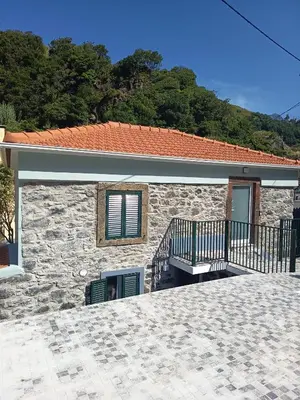 a stone house with a balcony and a building at Pousada Teixeira 11A in São Vicente