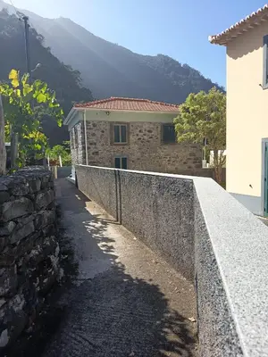 a house with a stone wall next to a building at Pousada Teixeira 11A in São Vicente