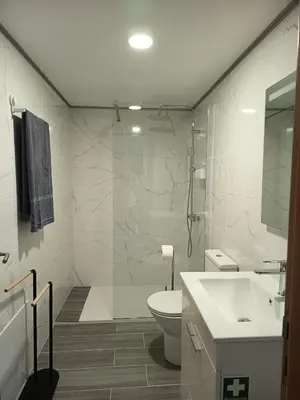 a white bathroom with a toilet and a sink at Pousada Teixeira 11B in São Vicente