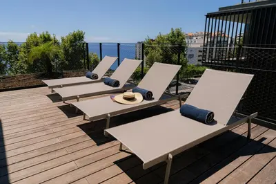 a row of chaise lounges on a deck at Savoy Monumentalis Ocean View By LM & AC Signature in Funchal