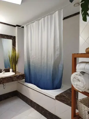 a bathroom with a shower with a blue shower curtain at Giraffa by Wanderlust Madeira - 3 Bedroom apartment in Funchal