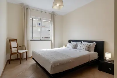 a bedroom with a bed with a chair and a window at Gonçalves Guest House by An Island Apart in Porto Santo