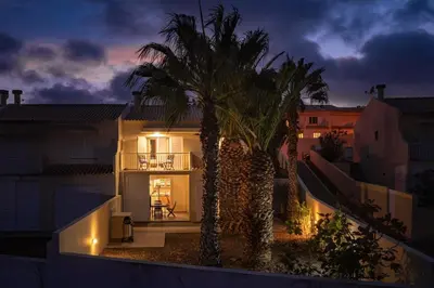 a palm tree in front of a house at night at Gonçalves Guest House by An Island Apart in Porto Santo