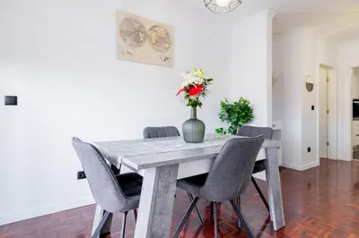 a dining room table with chairs and a vase with flowers at Carmo Lookout in Câmara de Lobos