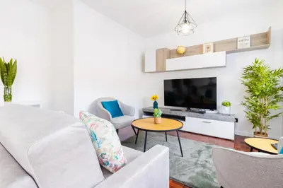 a living room with a white couch and a tv at Carmo Lookout in Câmara de Lobos