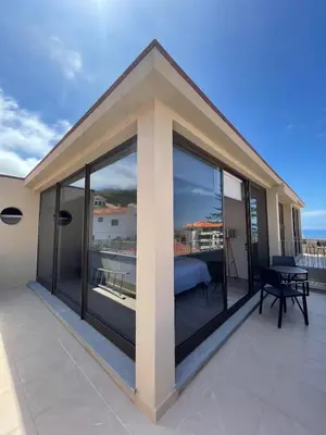 a balcony with large glass windows and a bed at Valhalla Madeira Apartements in Funchal