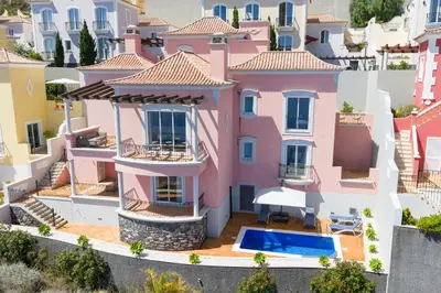 a swimming pool in a villa with an umbrella at Luxury Villa Pembe Palheiro Village by Holiday Rental Madeira in Funchal