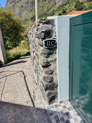 a stone fence in front of a house at Pousada Teixeira 11C in São Vicente