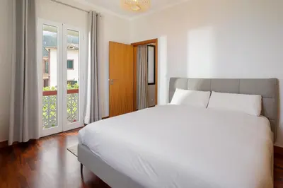 a bedroom with a large white bed and a window at Casa Jardim Celeste in Seixal