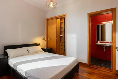 a bedroom with a bed and a bathroom with a sink at Casa Jardim Celeste in Seixal