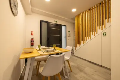 a dining room with a wooden table and white chairs at No Stress House in Paul do Mar