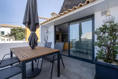 a dining table with an umbrella on a patio at No Stress House in Paul do Mar