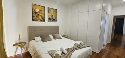a white bedroom with a large bed and a table at Achada View by Rentallido in Funchal