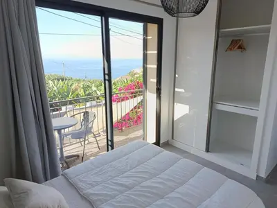 a bedroom with a bed and a view of a balcony at A Casa do Encanto da Ana & Luis in Ponta do Sol