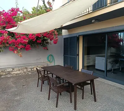 a wooden table and chairs next to a building with flowers at A Casa do Encanto da Ana & Luis in Ponta do Sol