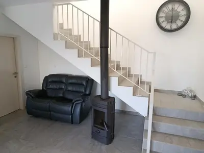 a fireplace in a living room with a chair and a clock at A Casa do Encanto da Ana & Luis in Ponta do Sol