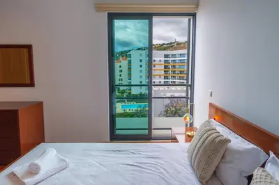 a bedroom with a bed and a large window at GuestReady - Modern space close to Formosa Beach in Funchal