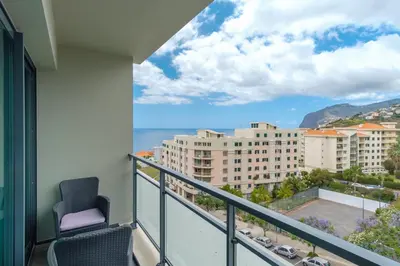 a balcony with a chair and a view of the ocean at GuestReady - Modern space close to Formosa Beach in Funchal
