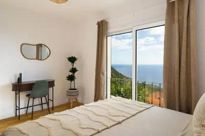 a bedroom with a bed and a desk and a large window at Villa Crossdeira - A Wellness Retreat in Arco da Calheta