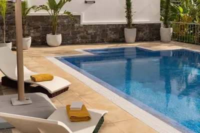 a swimming pool with two chairs and a table at Villa Crossdeira - A Wellness Retreat in Arco da Calheta