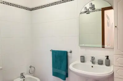 a white bathroom with a sink and a mirror at Armando House Ocean View in Gaula