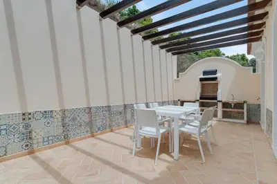 a patio with a white table and chairs at Villa Sol Palheiro Village by Holiday Rental Madeira in Funchal