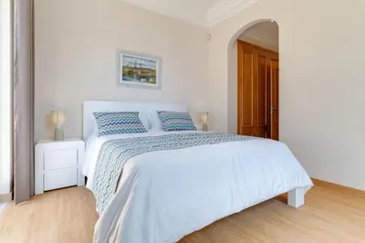 a white bedroom with a white bed with blue pillows at Villa Sol Palheiro Village by Holiday Rental Madeira in Funchal