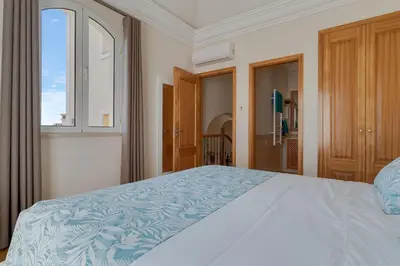 a bedroom with a large bed with a blue blanket at Villa Sol Palheiro Village by Holiday Rental Madeira in Funchal