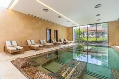 an indoor swimming pool with chairs and a large window at Villa Sol Palheiro Village by Holiday Rental Madeira in Funchal