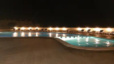 a swimming pool at night with chairs and lights at Sea View Apartment in Lagos