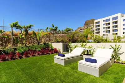two white chairs sitting on the grass in a yard at Star Lit Jacuzzi Apartment in Câmara de Lobos