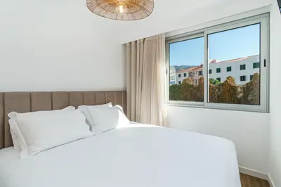 a bedroom with a white bed and a window at Star Lit Jacuzzi Apartment in Câmara de Lobos