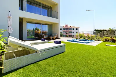 a backyard of a house with a green lawn at Star Lit Jacuzzi Apartment in Câmara de Lobos