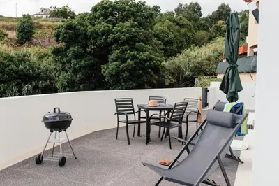 a patio with a grill and a table and chairs at Casa Piquita in Estreito da Calheta