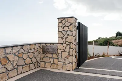 a stone wall with a gate on a road at Casa Piquita in Estreito da Calheta