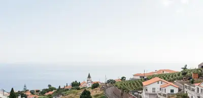a view of a town on a hill next to the ocean at Casa Piquita in Estreito da Calheta