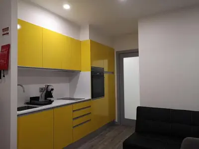 a kitchen with yellow cabinets and a black couch at Apartamento moderno no Funchal - Araçá Apartment by Tropical Solutions in Funchal