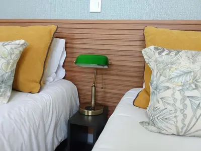 a green lamp on a table between two beds at Apartamento moderno no Funchal - Araçá Apartment by Tropical Solutions in Funchal