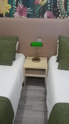 a room with two beds and a green lamp on a table at Apartamento moderno no centro do Funchal - Tabaibo By Tropical Solutions in Funchal