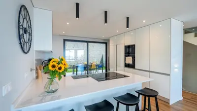 a kitchen with a counter with stools and a vase of flowers at Villa Nero by LovelyStay in Funchal