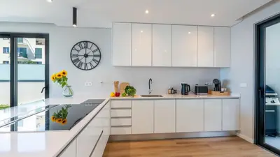 a kitchen with white cabinets and a clock on the wall at Villa Nero by LovelyStay in Funchal