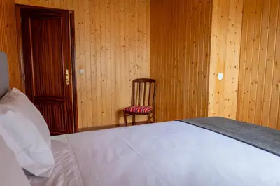 a bedroom with a white bed and a chair at Casa Do Senhor, By OP in São Vicente