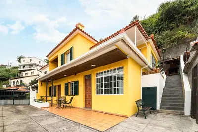 a yellow house with chairs in front of it at Sol Poente by GALMI in Funchal