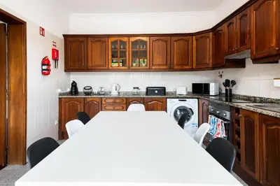 a kitchen with wooden cabinets and a white table with chairs at Sol Poente by GALMI in Funchal