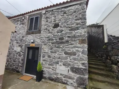 a stone house with a blue door and stairs at Alojamiento Local - Estrela in Seixal
