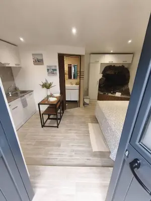 a room with a bed and a table and a kitchen at Alojamiento Local - Estrela in Seixal