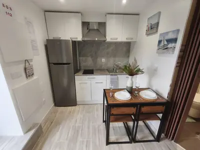 a small kitchen with a table and a refrigerator at Alojamiento Local - Estrela in Seixal